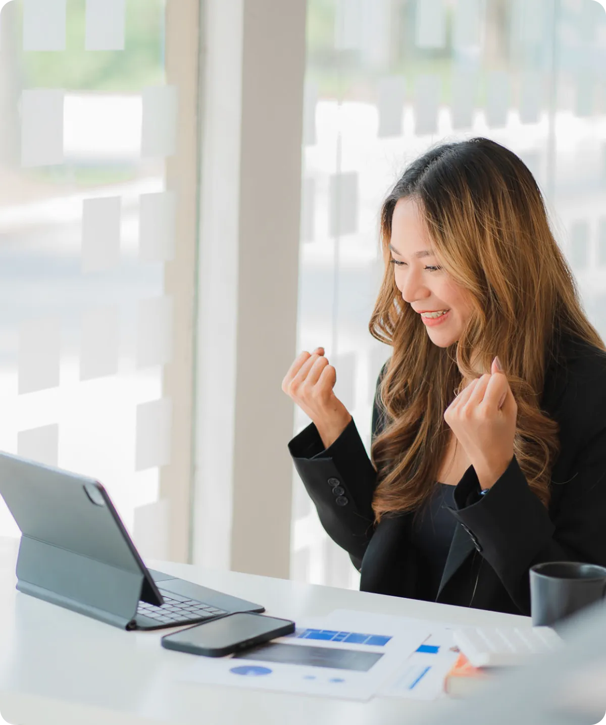 Woman celebrating success at tablet in office.