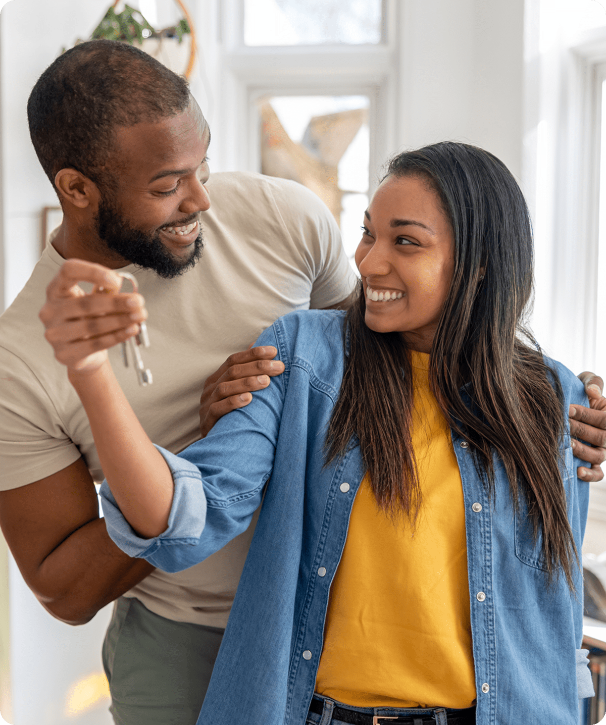 Couple smiling, holding house keys happily.