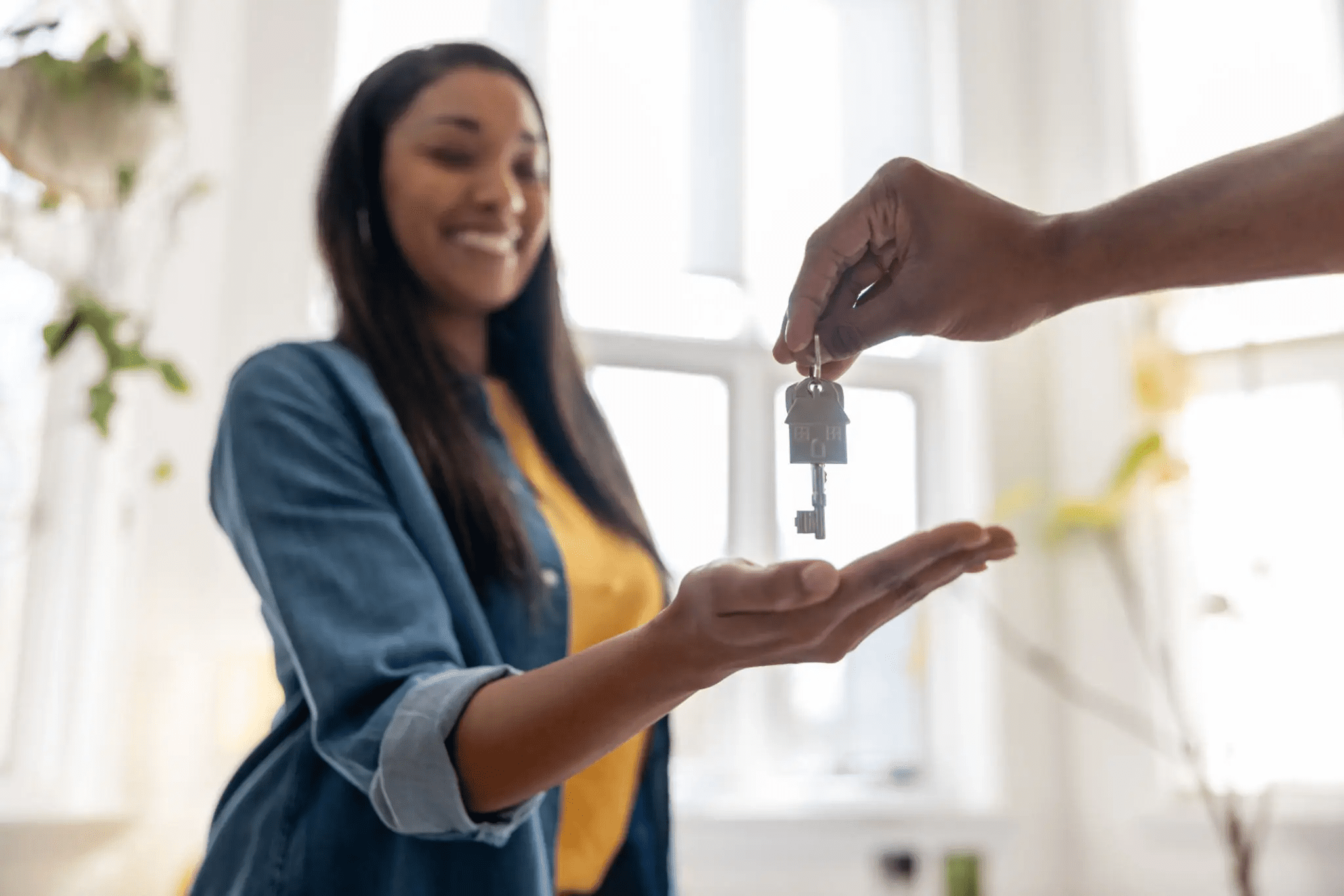 A woman happily receiving house keys from a person.