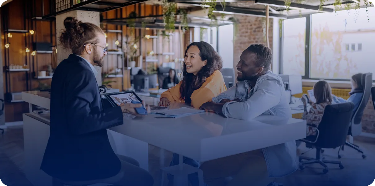 Office meeting with three people at table.