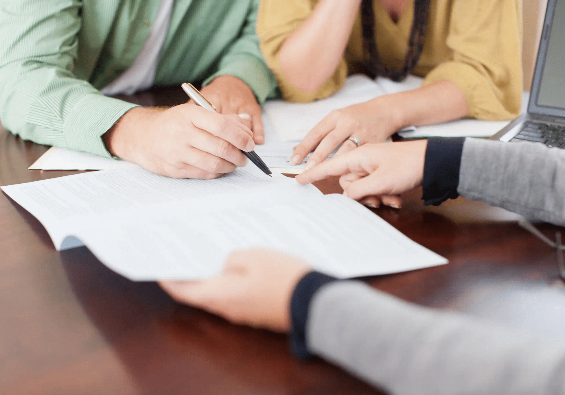 People reviewing and signing documents together at a table.