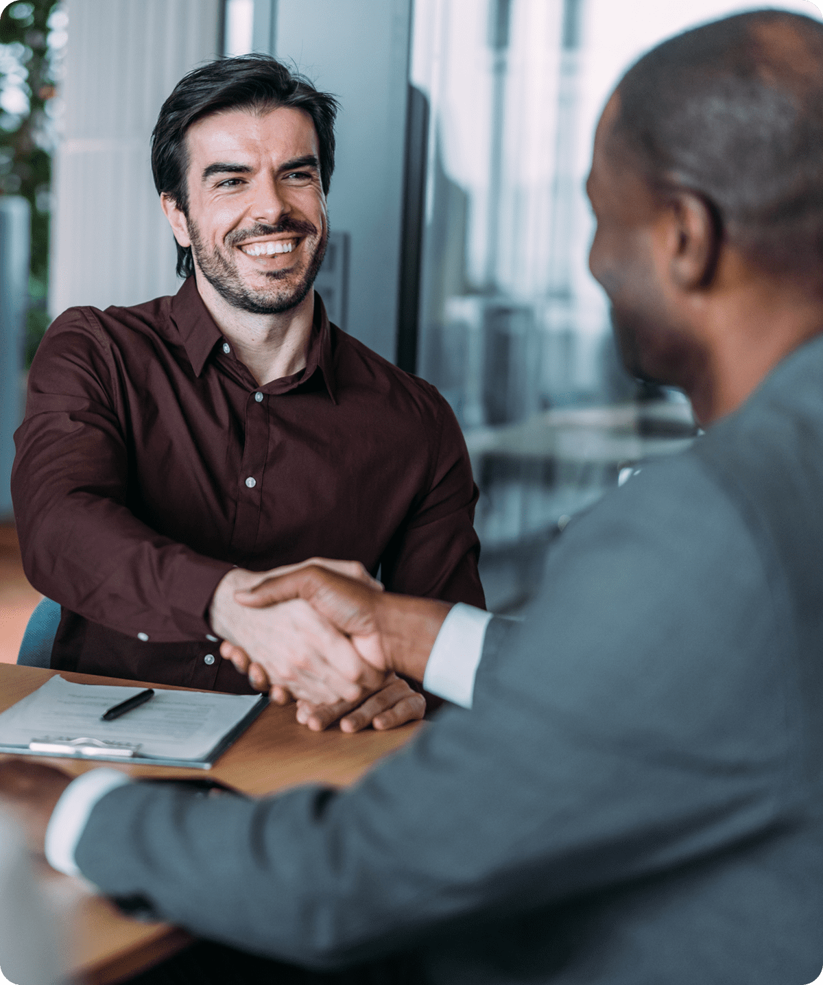Two people shaking hands in office.
