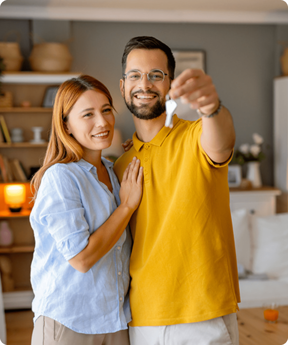 Couple smiling and holding house keys.